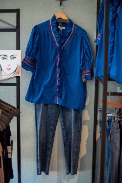 Royal blue embroidered blouse with jeans on a clothing display